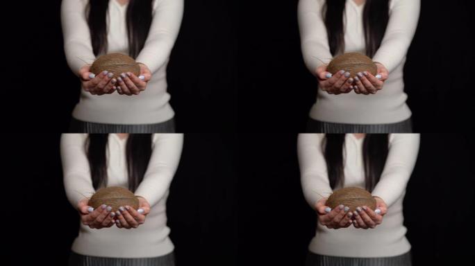 女人在黑色背景上展示手中的椰子。