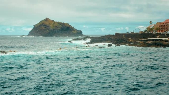 加那利群岛西部的海湾。海洋中的一块大石头岩石，海浪拍打着白色泡沫的石头。西班牙加拉奇科