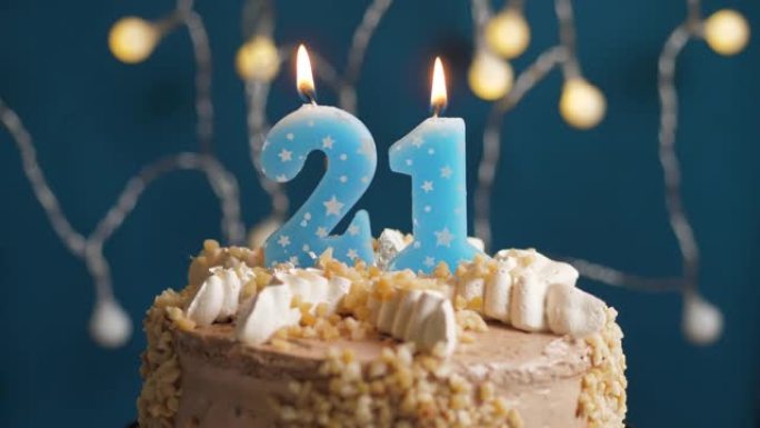 蓝色背景上有21号蜡烛的生日蛋糕。蜡烛吹灭了。慢动作和特写视图