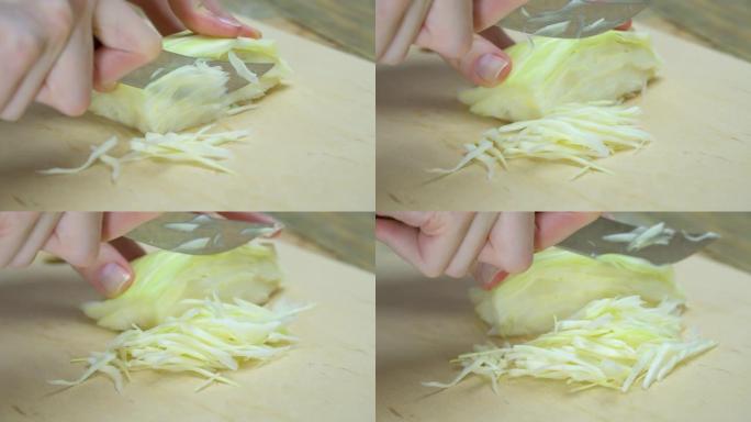 厨师在木砧板上切碎纳帕卷心菜的亚洲凉拌卷心菜的特写镜头，选择性聚焦。健康食品准备。
