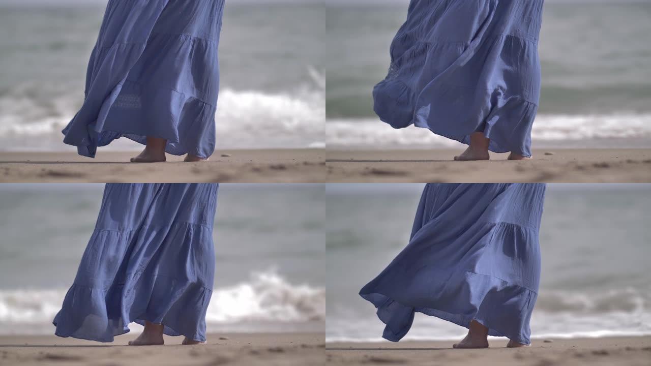 女人蓝色裙子在海岸的风中发展