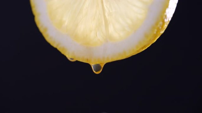 以4k分辨率在黑色背景上慢动作从柠檬切片中滴落的蜂蜜
