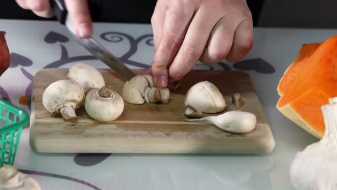 女人在厨房的木板上切蘑菇。女性手准备奶油汤配南瓜和蘑菇。健康饮食理念