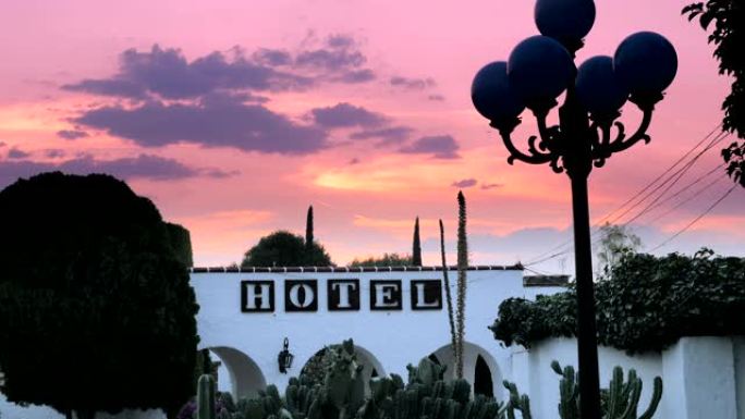 白色拱形墙上的酒店标志，映衬着戏剧性的日落