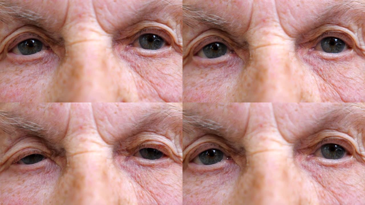 老年妇女看着沉思对着镜头的肖像。皱纹女性脸的特写。面部表情平静的祖母。慢动作细节视图