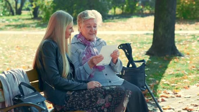 老妇人在公园里读一封信给年轻漂亮女人的中间特写