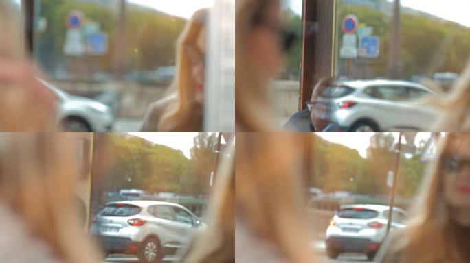 一个戴着墨镜的金发美女，看着她在商店橱窗里的倒影。汽车在后台经过。法国巴黎