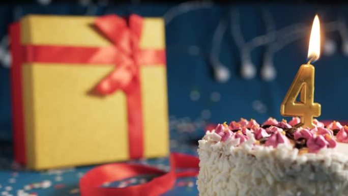 白色生日蛋糕4号点火器燃烧的金色蜡烛，蓝色背景带灯和用红丝带捆绑的礼物黄色盒子。特写