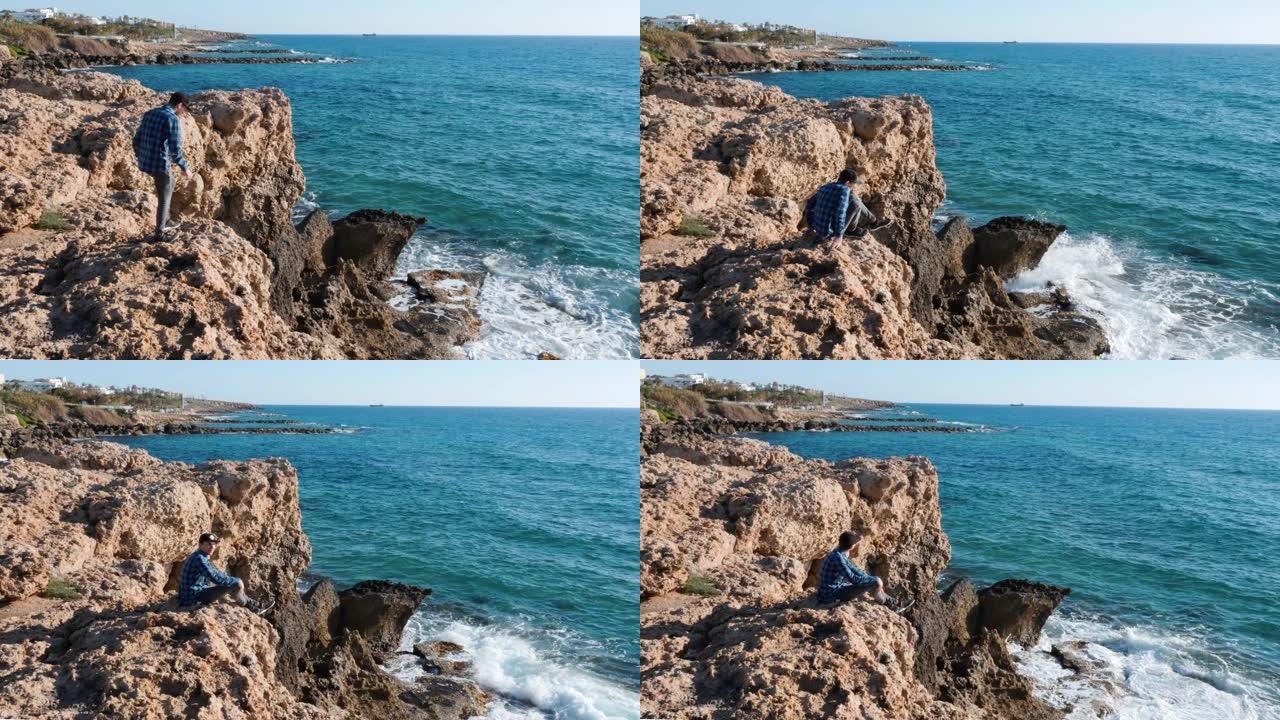 那家伙坐在悬崖边。小男孩来到悬崖边坐下。男人坐着看着地平线。男孩来到悬崖边，坐在岩石上。孤独的家伙坐