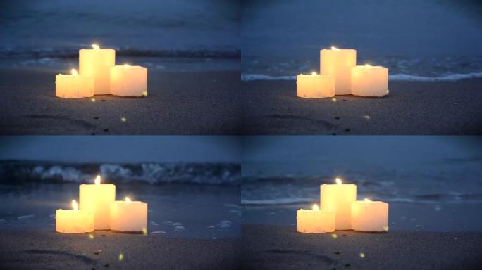 海洋海浪燃烧附近的沙滩上三支小蜡烛