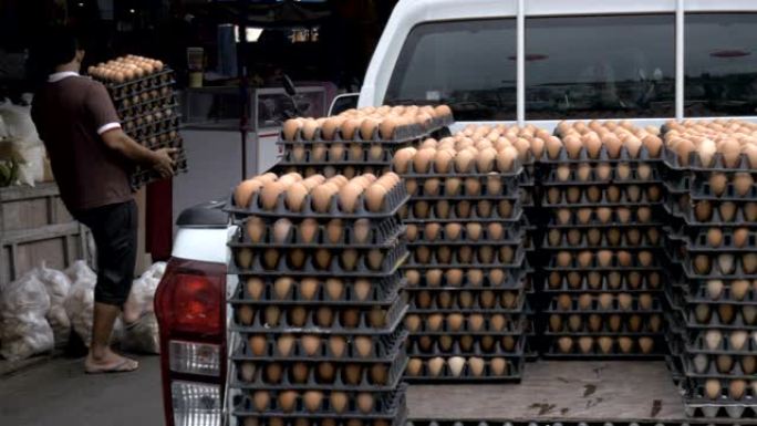 一名男子将一箱鸡蛋从皮卡车的后部带入市场