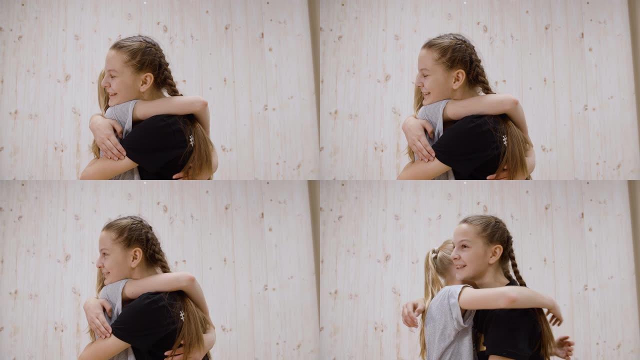 快乐的女孩朋友拥抱在光工作室背景上的会议。两个女孩少年在友好相遇时拥抱。