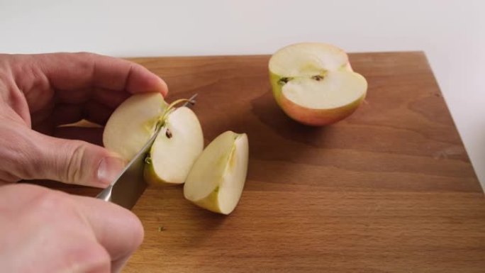 人用刀在木板上切一个红苹果。
