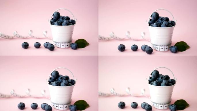 粉红色背景的夏季蓝莓桶。浆果设计。关闭俯视图或平铺，放置文本。概念医疗饮食