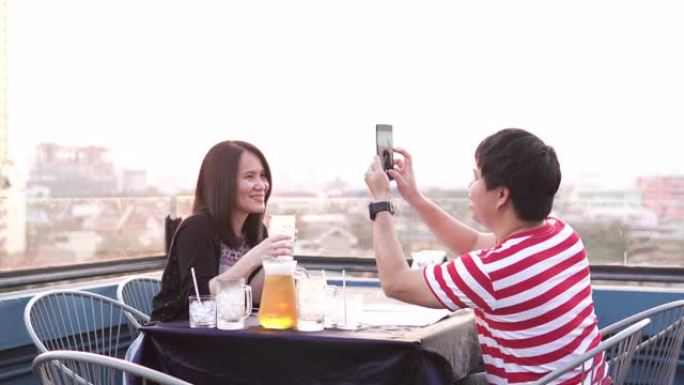 夫妇在户外屋顶用智能手机拍照。