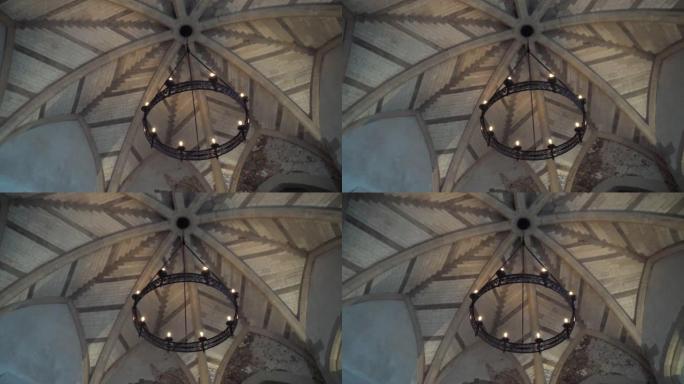 从底部观看旧吊灯的形式，轮子上的灯泡挂在教堂或另一栋旧建筑的天花板上。行动。漂亮的复古风格