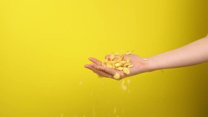 手捕捉黄色背景上的玉米片