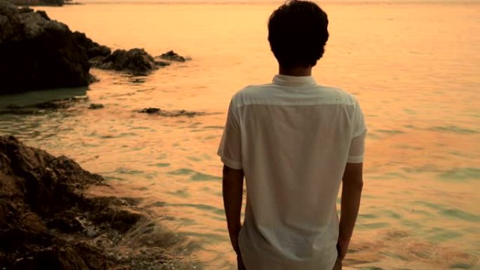 亚洲年轻人在沙滩上放松并看着大海的后景
