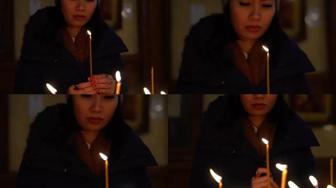 亚洲妇女在教堂里祈祷并点燃蜡烛