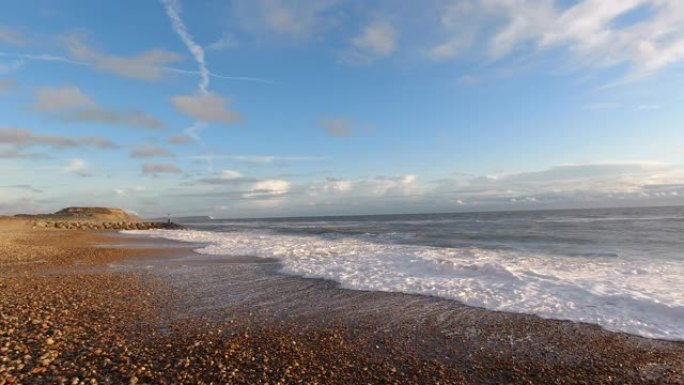在雄伟的蓝天白云下，石质海滩上海浪撞击的慢动作 (120 fps) 镜头