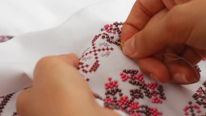 针线特写，用珠子绣花图案。手工缝制婚纱。