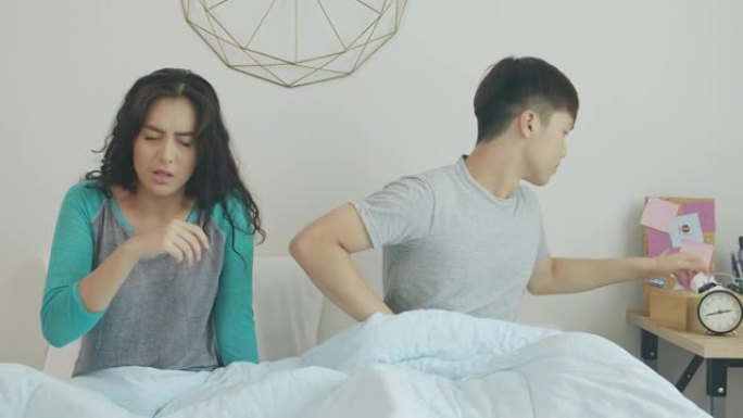 亚洲女人在床上打喷嚏，他的男朋友为她拿起纸巾。