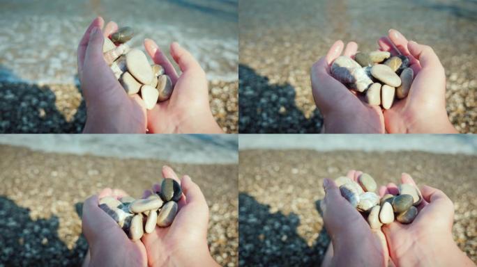 一个人坐在海边的海滩上时拿着一把鹅卵石
