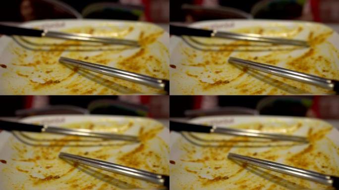 在餐厅吃完食物后空盘子。用两双筷子。背景模糊是一个小女孩在饭后看书。