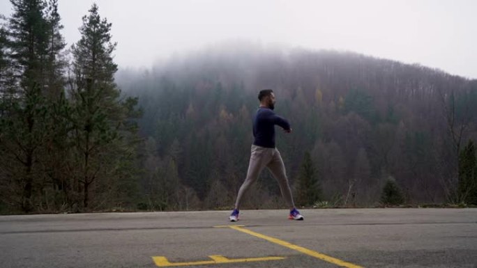 健康强壮男人的前视图。在雾蒙蒙的日子里，男人在户外慢跑前伸展肌肉