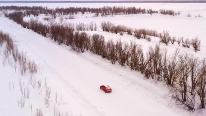 一辆汽车正沿着冬季白雪皑皑的乡间小路行驶。无人机的鸟瞰图