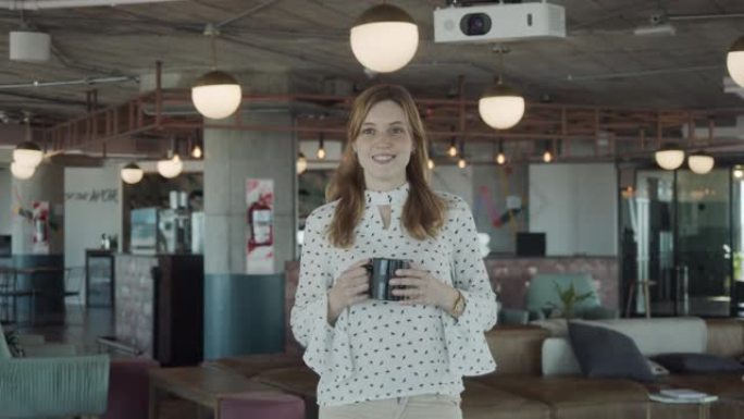 一名年轻成年女子在现代办公室休息，喝咖啡的慢动作视频