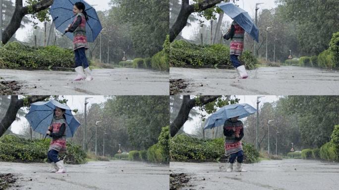 一个小女孩在水坑里跳伞的慢动作在雨中撑着伞