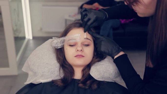 专业大师眉女在美容院中去除眉毛上的薄膜并去除眉毛上的液体