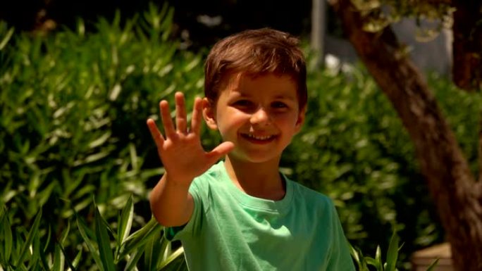 一个穿着绿色t恤的快乐男孩露出张开的手掌