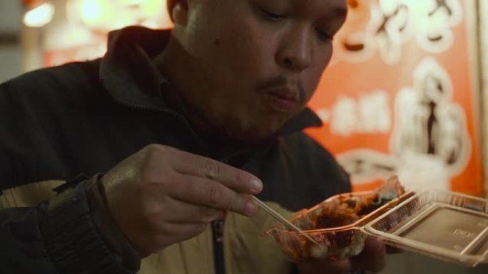 亚洲旅游男子吃章鱼烧，球形日本小吃时感觉很热。