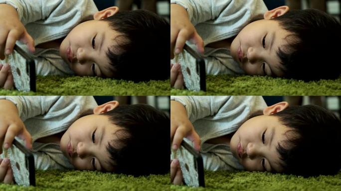 孩子在地板上玩手机。年轻的亚洲男孩使用手机。集中情绪。