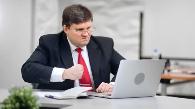 怒火中烧的男老板一边狂怒地敲打着桌子，一边看着红色摄像头拍下的笔记本电脑屏幕