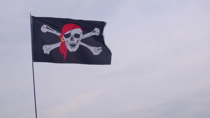 海盗旗乔利·罗杰 (Jolly Roger) 在大风天挂在蓝天背景上的船桅杆上。