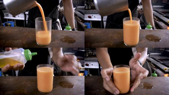 厨师将橙色饮料倒入凉爽的玻璃杯中，并将其送达相机