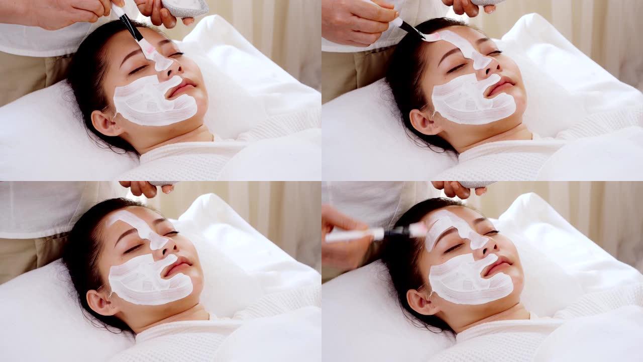 亚洲女性在接受面部护理时放松身心，在脸上涂抹面霜、水疗