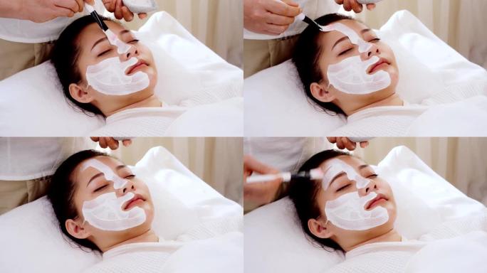 亚洲女性在接受面部护理时放松身心，在脸上涂抹面霜、水疗