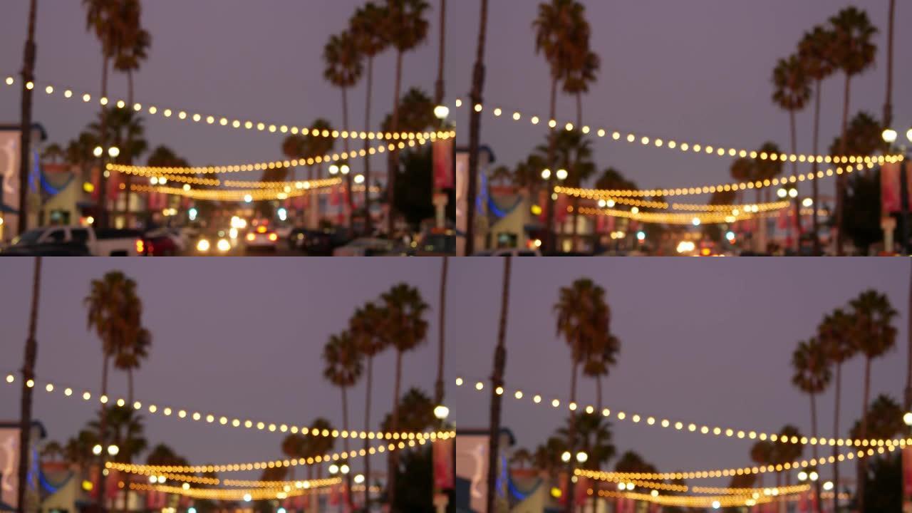 装饰性的凝视花环灯，棕榈树轮廓，傍晚的天空。背景模糊。加州用灯装饰的街道。节日照明、海滩派对、热带度