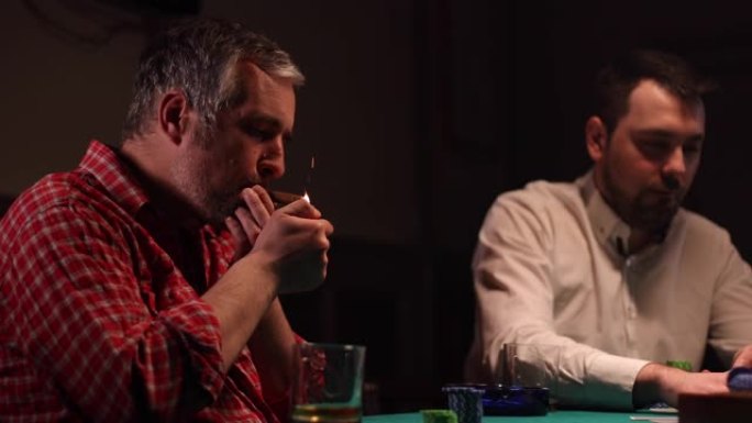 男子在暗室玩扑克时抽雪茄