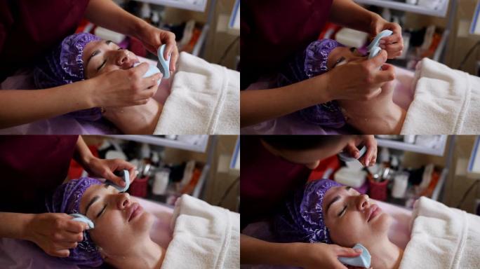 美容师在停用抗衰老美容面膜后擦拭患者的面部。