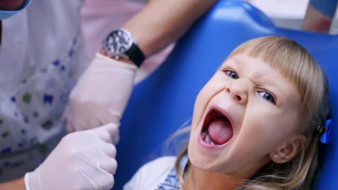 口腔科椅子上的小孩张开嘴，向医生展示牙齿