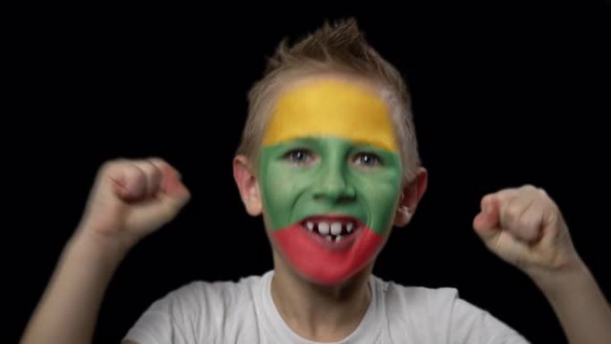快乐的男孩为他最喜欢的立陶宛队的胜利而欢呼。脸上涂着民族色彩的孩子。