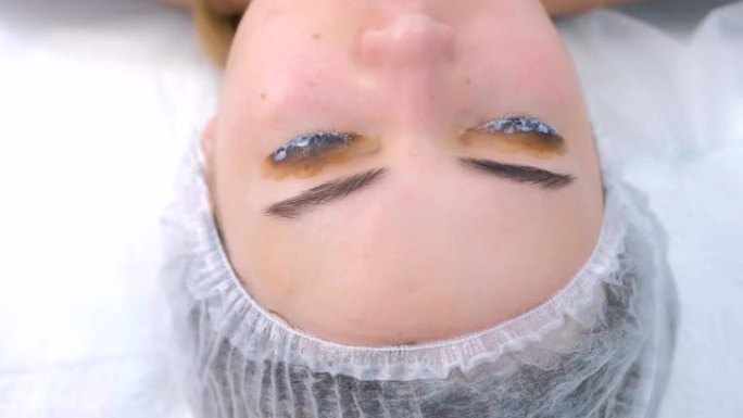 女人在睫毛上层压溶液，提起睫毛程序，特写。