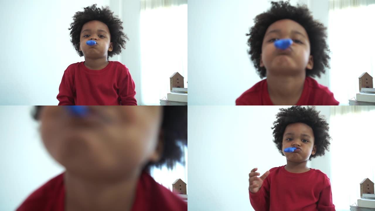 非裔美国人的小男孩试图吹小气球