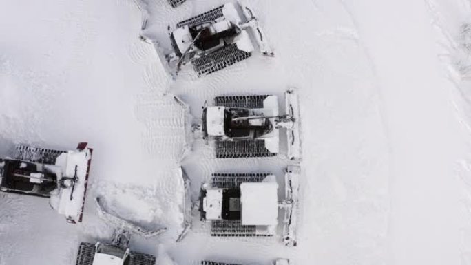 雪猫站在山区冬季滑雪胜地的雪地停车场上。避暑山庄冬季斜坡上无人驾驶雪美容机的俯视图