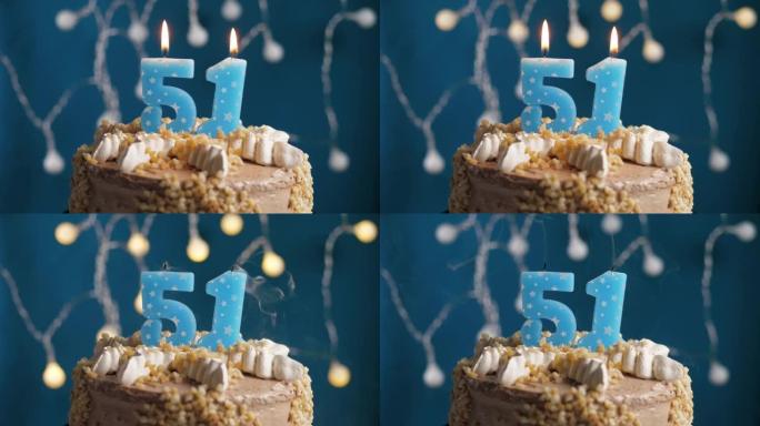 蓝色背景上有51号蜡烛的生日蛋糕。蜡烛吹灭了。慢动作和特写视图